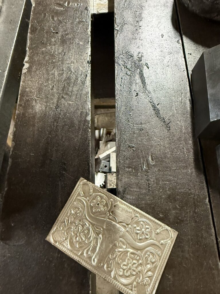 A pressed silver plate lying beside die steel
