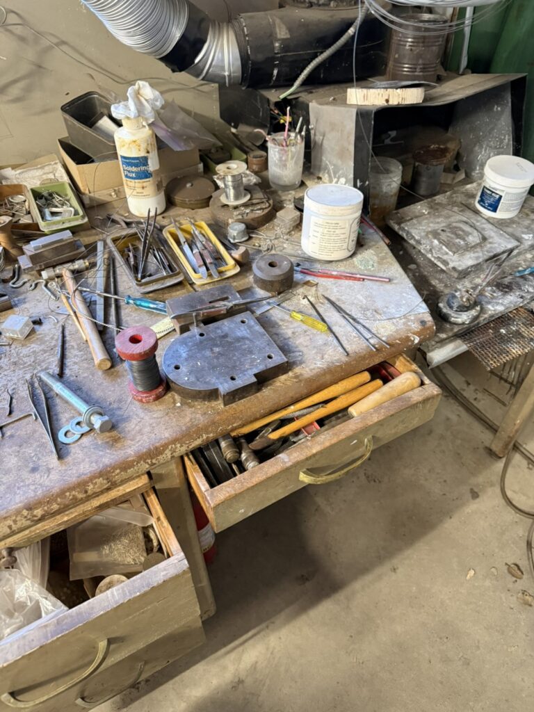 A workbench covered with gravers, hand tools and stamped silver plates